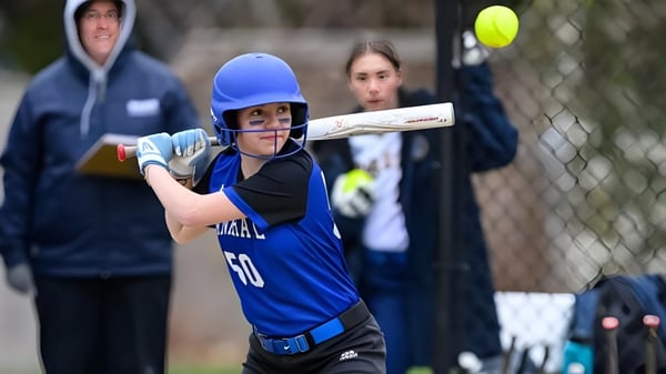 Un estudiante de la Dana Hall School sostiene un bate de béisbol y se prepara para un golpe.