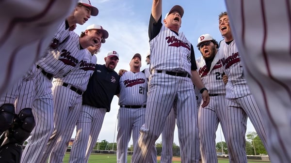 Estudiantes de la Danville Community High School celebran juntos en el campo de béisbol bajo un cielo despejado.