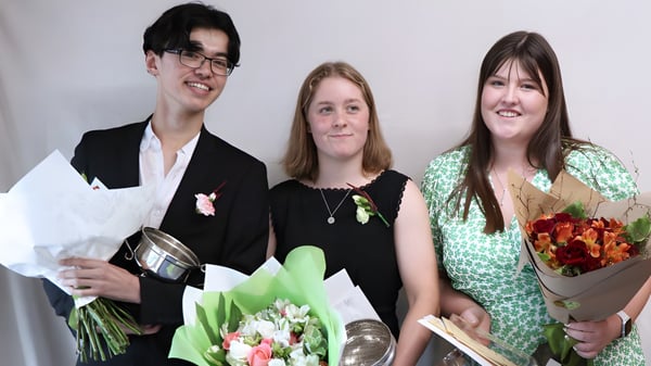 Tres personas sostienen ramos de flores en una celebración en el campus de la Darfield High School.
