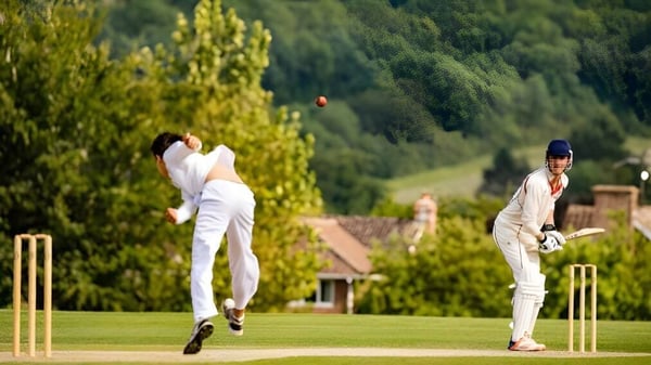 Dos alumnas juegan en el campo de cricket de Dauntsey’s School con uniformes blancos.
