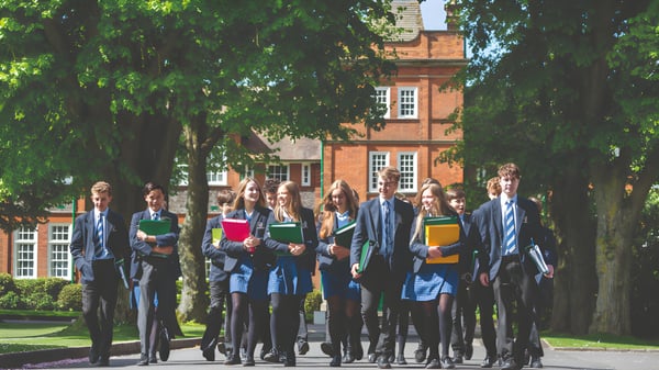 Un grupo de estudiantes está frente a un edificio histórico de ladrillo en el terreno de la Dauntsey’s School.