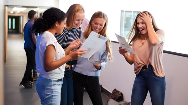 Estudiantes del David Game College discuten juntos los resultados de los exámenes en el pasillo.