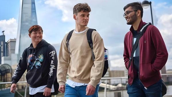 Tres jóvenes están en un entorno urbano con vista a la ciudad en el campus del David Game College Liverpool.