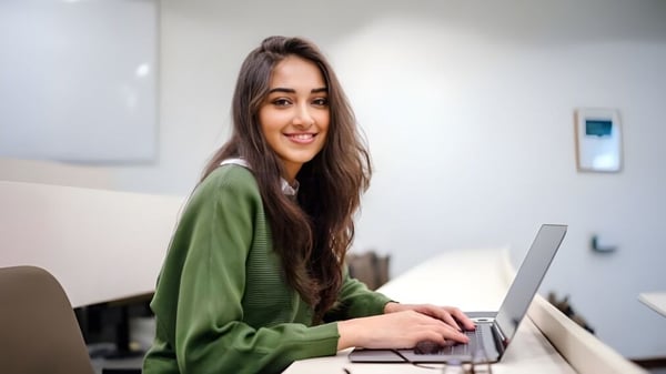 Una joven está sentada en el escritorio y utiliza una laptop en el área de trabajo del David Game College Liverpool.