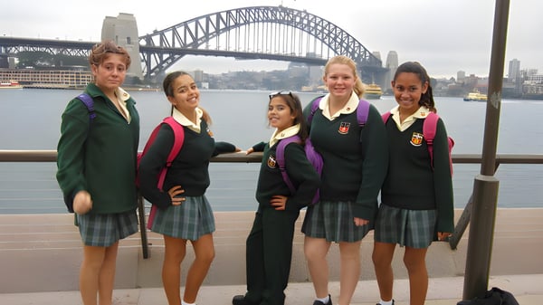 Un grupo de estudiantes de la Davidson High School posan frente al Puente del Puerto de Sídney con el horizonte de la ciudad al fondo.