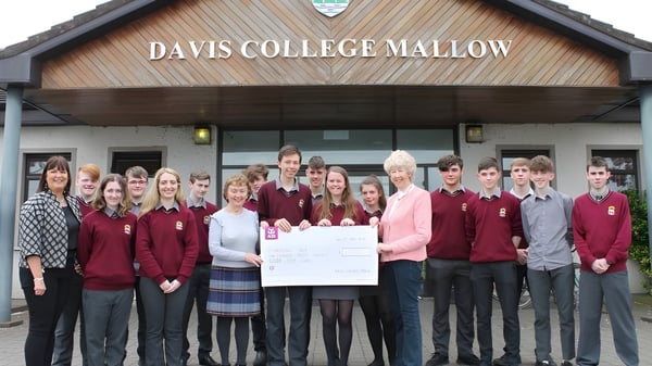 Estudiantes del Davis College están en uniforme escolar frente al edificio con el letrero Davis College Mallow.