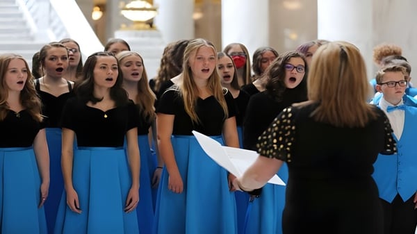 Un grupo de alumnas del Davis School District se presenta en un escenario con un fondo decorado.