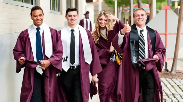 Cuatro graduados del Davis School District con togas rojas caminan juntos por un camino pavimentado en el campus escolar.