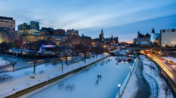Un canal congelado frente a la École secondaire publique De La Salle iluminado por luces de la ciudad por la noche.
