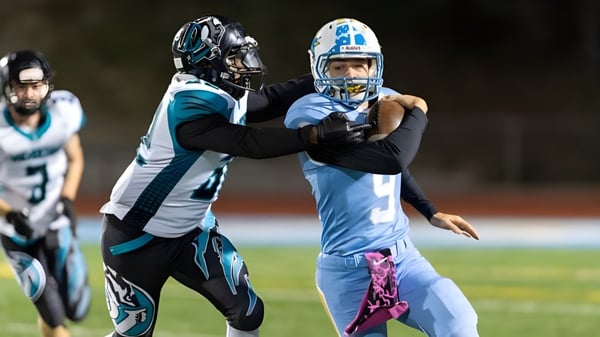 Dos jugadores de fútbol americano de Deer Valley Unified luchan en el campo durante un partido.