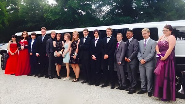 Un grupo de alumnas y alumnos de la Denefield School está vestido formalmente en un prado con árboles de fondo.