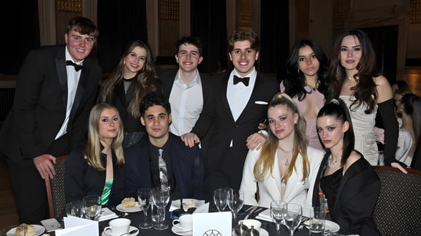 Estudiantes del DLD College London participan en una cena formal en una mesa elegantemente puesta.