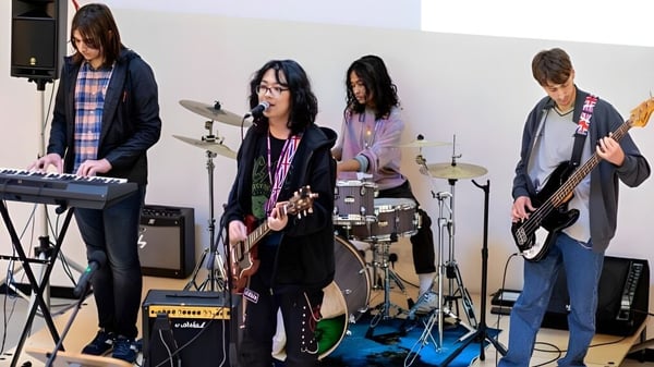 Un grupo de músicos se presenta en el escenario del DLD College London con varios instrumentos y equipo.