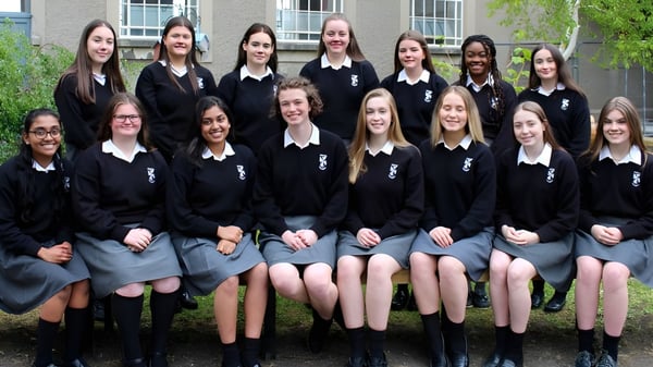 Un grupo de alumnas del Dominican College Sion Hill está frente a un edificio con grandes ventanas.
