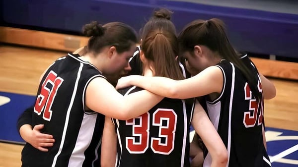 Un grupo de jóvenes jugadoras de baloncesto está abrazadas en la cancha de la Dominion Academy of Dayton.
