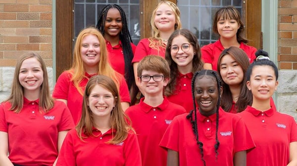 Un grupo de alumnas de la Dominion Academy of Dayton posan sonriendo frente a un edificio de ladrillos.