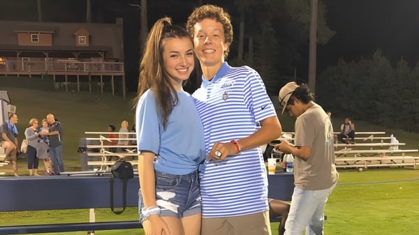 Una joven pareja se abraza y sonríe en el campo deportivo de la Dominion Christian School.