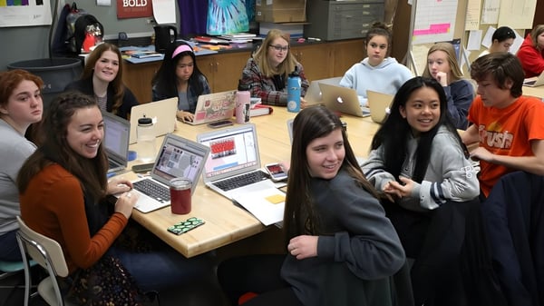 Un grupo de estudiantes del Don College trabaja en conjunto con laptops en una mesa en el aula.