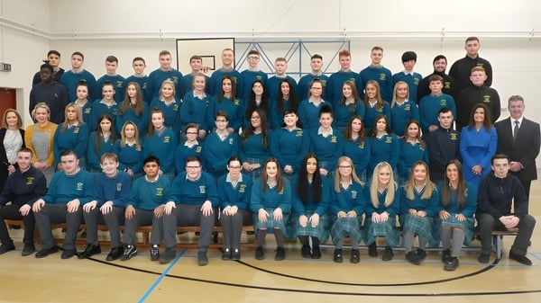 Un gran grupo de estudiantes de la Donahies Community School está sentado en uniformes escolares azules y negros durante una asamblea.