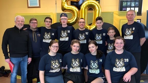 Estudiantes y profesores de Dorset Collegiate se reúnen frente a un gran 50 dorado como celebración del aniversario.