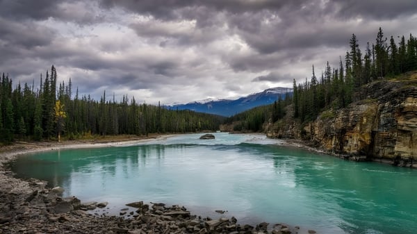 Un tranquilo paisaje fluvial con agua turquesa y montañas al fondo en el terreno de Dorset Collegiate.
