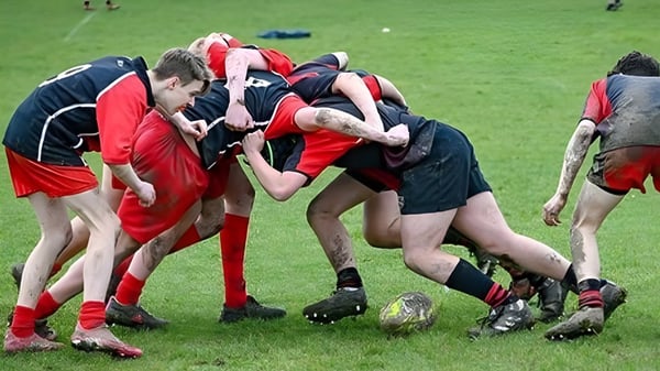 Un grupo de jugadores de rugby en camisetas rojas y negras en un scrum en el campo del Dover College.