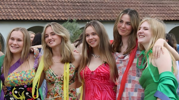 Un grupo de estudiantes femeninas posan riendo frente a un edificio con techo de tejas en el campus de la Downe House School.