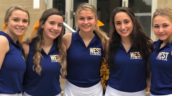 Cinco estudiantes del Downingtown Area School District posan juntas en sus uniformes de cheerleading en una instalación deportiva.