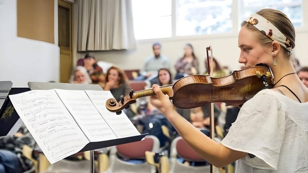 Una estudiante del Downingtown Area School District toca el violín frente a un público.