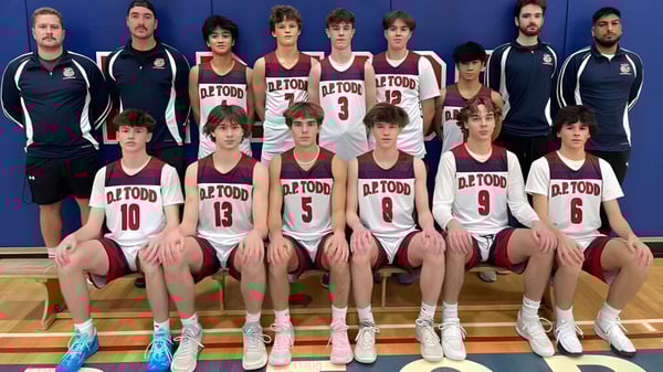 Un grupo de jóvenes jugadores de baloncesto posan juntos en el gimnasio de la D.P. Todd Secondary School.