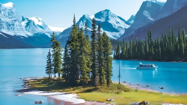 Un tranquilo lago alpino con montañas cubiertas de nieve y una orilla boscosa en la región de Drumheller Valley.