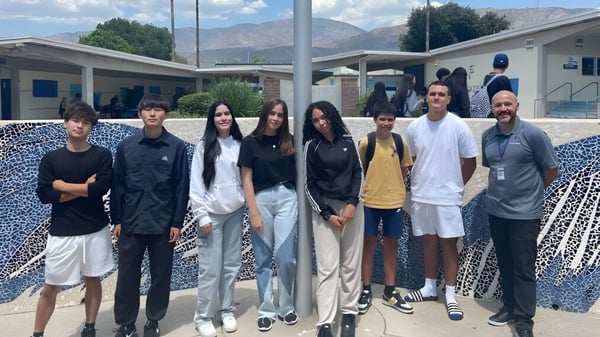 Un grupo de estudiantes está frente a un edificio con montañas en el fondo en el terreno del Duarte Unified School District.