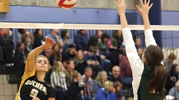 Estudiantes de la Duchess Park Secondary School juegan al voleibol mientras los espectadores en el fondo siguen el juego.