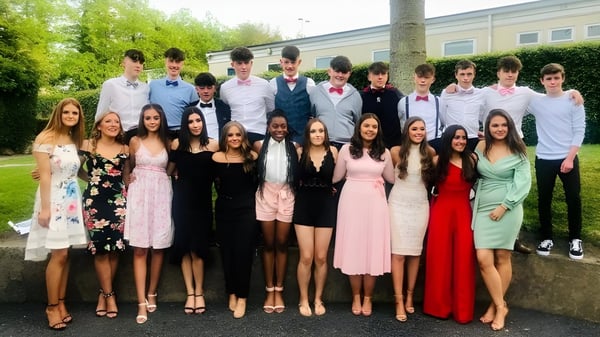Un grupo de alumnas y alumnos del Duiske College está reunido frente a un edificio al aire libre.