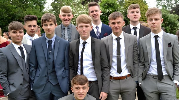 Un grupo de estudiantes del Dulwich College está vestido formalmente al aire libre frente a árboles y áreas verdes.