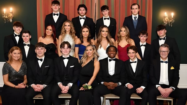 Un grupo de personas vestidas formalmente posan en una sala festiva en el campus de la Dundalk Grammar School.