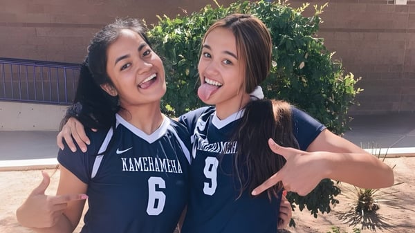 Dos estudiantes de la Durango High School se abrazan afuera frente a un fondo verde.