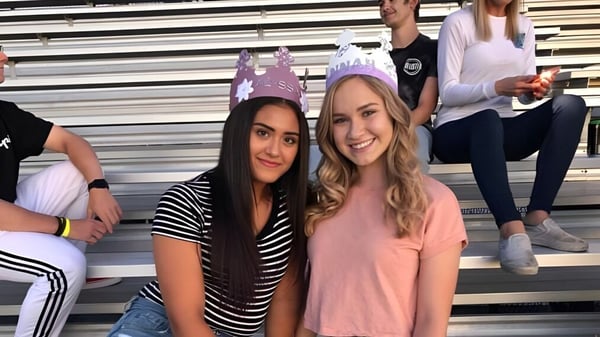 Dos estudiantes posan juntas frente a una tribuna en el terreno de la Durango High School.