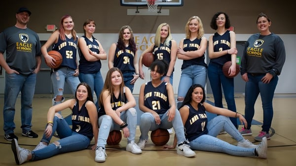 Un grupo de estudiantes de la Eagle School posan juntos en la cancha de baloncesto con uniformes a juego.