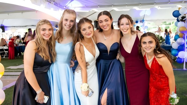 Un grupo de jóvenes mujeres en ropa festiva posan al aire libre en el campus de la Earlscliffe School con globos de fondo.