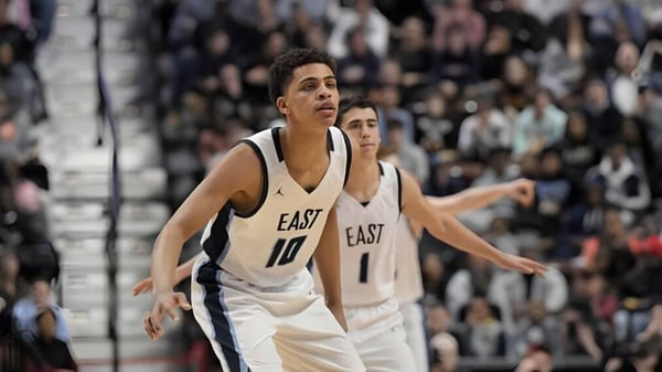 Un jugador de baloncesto de la East Catholic High School está en la cancha frente a una gran multitud.