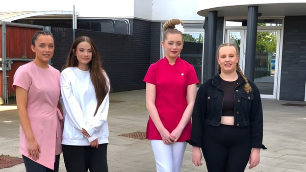 Cuatro estudiantes están juntos frente a un edificio en el campus del East Sussex College Lewes.