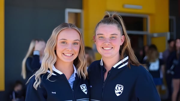 Dos estudiantes en uniforme escolar posan frente a una pared amarilla en el campus de la Eastern Fleurieu R-12.
