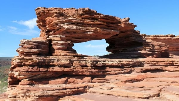 Una formación natural de arco de roca de arenisca rojo-marrón se puede ver frente a un cielo claro cerca de la Eastern Hills Senior High School.