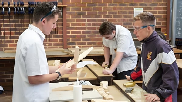 Estudiantes de la Eastern Hills Senior High School trabajan juntos en un proyecto de madera en el taller.