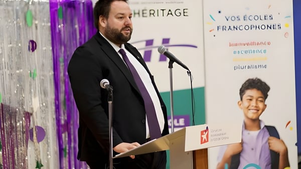 Un hombre en traje da un discurso en el podio en un evento de las Eastern Ontario Public Schools.