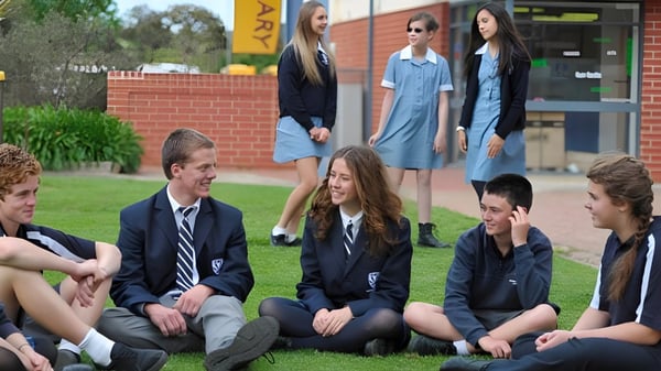 Un grupo de estudiantes de la Eastern Fleurieu R-12 está al aire libre frente a un edificio de ladrillo y conversan.