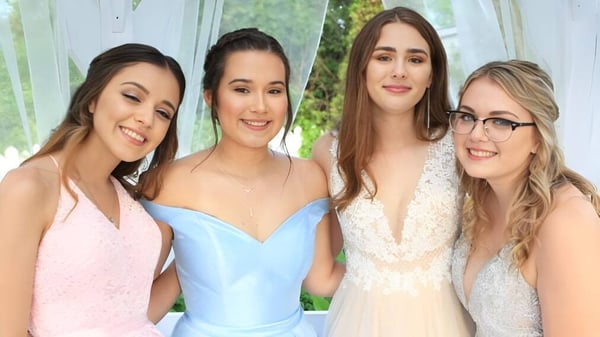 Cuatro estudiantes de la Eastside Secondary School posan frente a una ventana con vista verde al exterior.