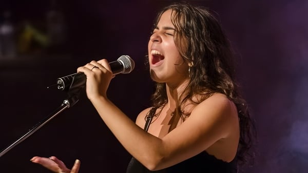 Una alumna de la École Secondaire Augustin-Norbert-Morin canta apasionadamente en un micrófono en un escenario.