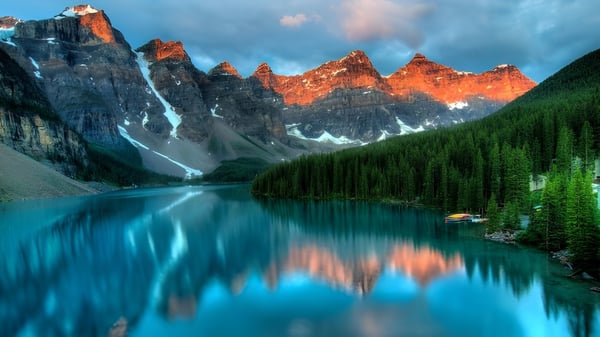 Un tranquilo lago alpino con montañas cubiertas de nieve se refleja en el agua en el campus de la École Aux quatre vents.
